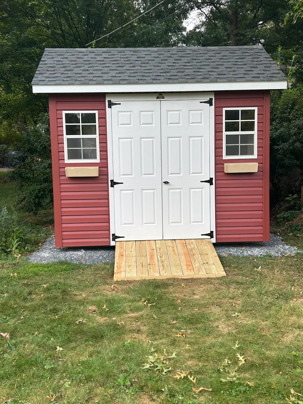 Custom backyard shed, red exterior with white doors and walkway.