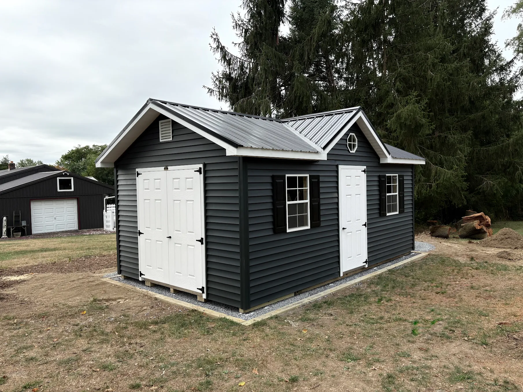 Custom backyard shed, dark exterior with white double doors and accents.