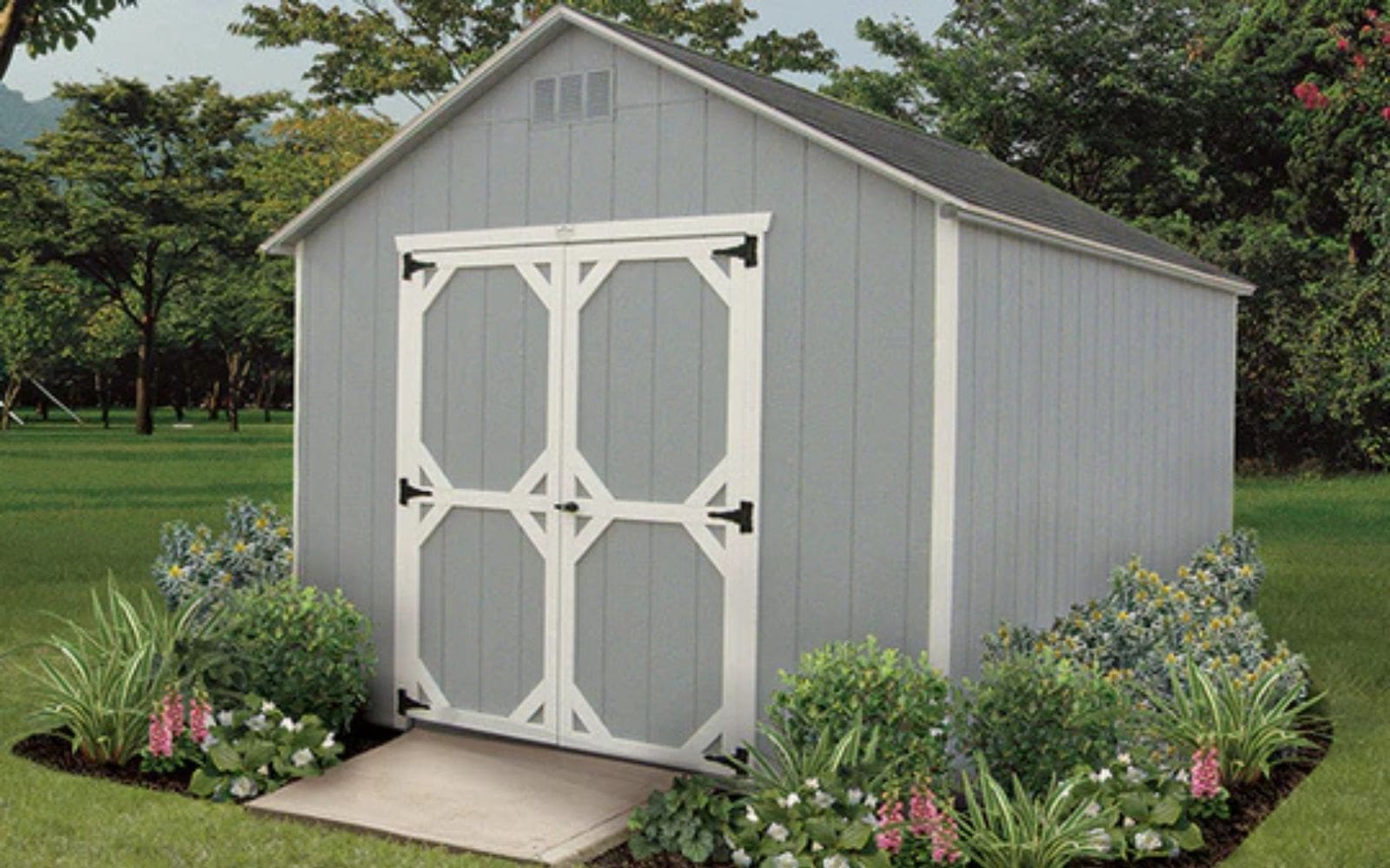 Grey custom backyard shed with white accents surrounded by a garden.