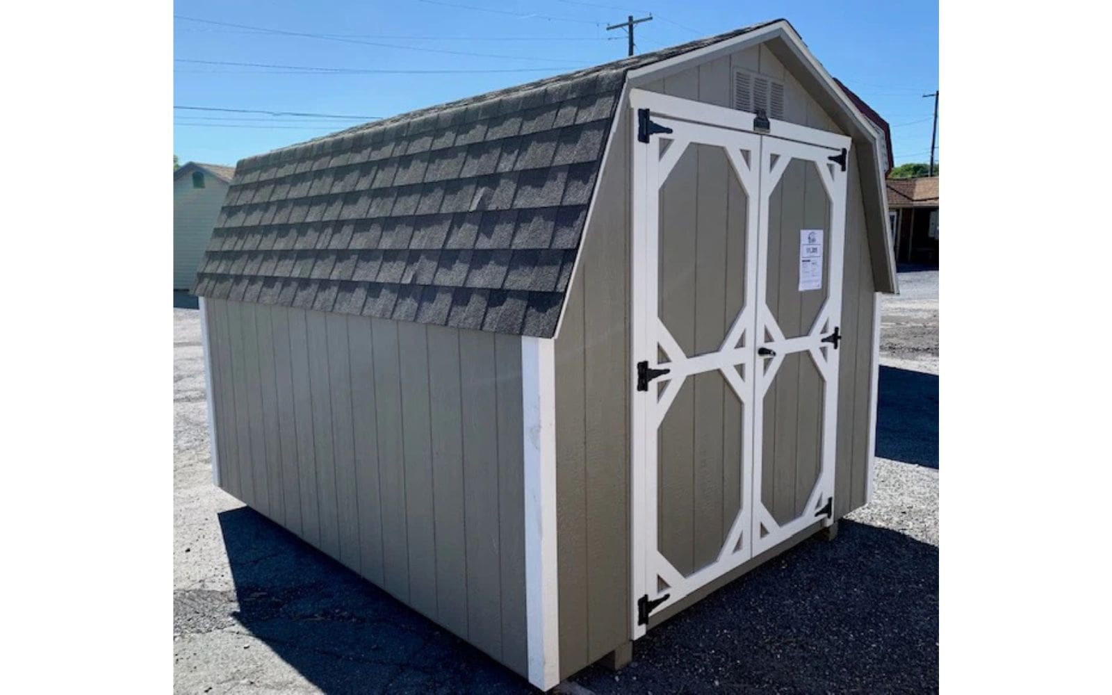 Grey backyard shed with white accented doors and barn shaped roof.