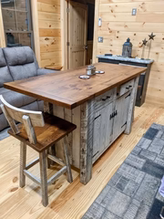 Rustic cabin interior with a wood-top kitchen island and bar stools.