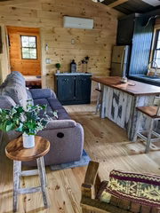 Wide view of a wood-paneled cabin interior with sofa, kitchen cabinets, and island.