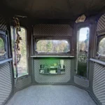 Interior of Redneck hunting blind with gun carrier, windows, carpet, sound treated walls, and storage space.