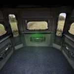 Interior of Redneck hunting blind with gun carrier, windows, carpet, sound treated walls, and storage space.