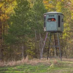 Redneck elevated hunting blind with hunter using a gun bow to shoot in the woods.