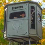 Redneck elevated hunting blind with hunter using a camouflage bow to shoot.