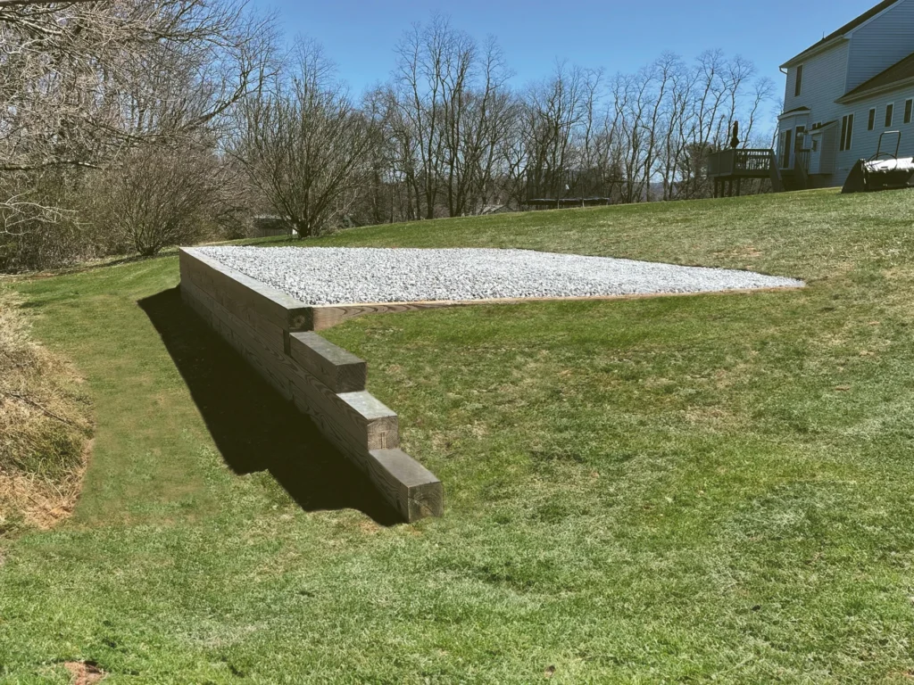 Prepared stone shed pad with a timber retaining edge.