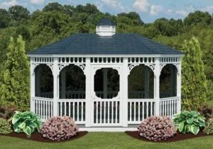 Custom beautiful white gazebo with a door and grey roof located in a garden.