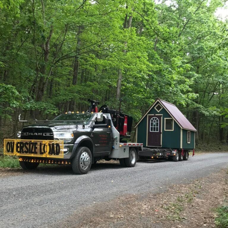 Transportation and delivery of custom shed by Esh's Sheds on a road next to the woods.