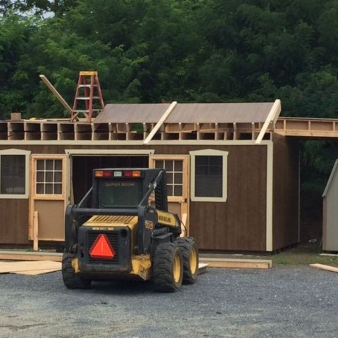 Construction of Esh's Sheds custom shed with brown exterior and construction vehicle.