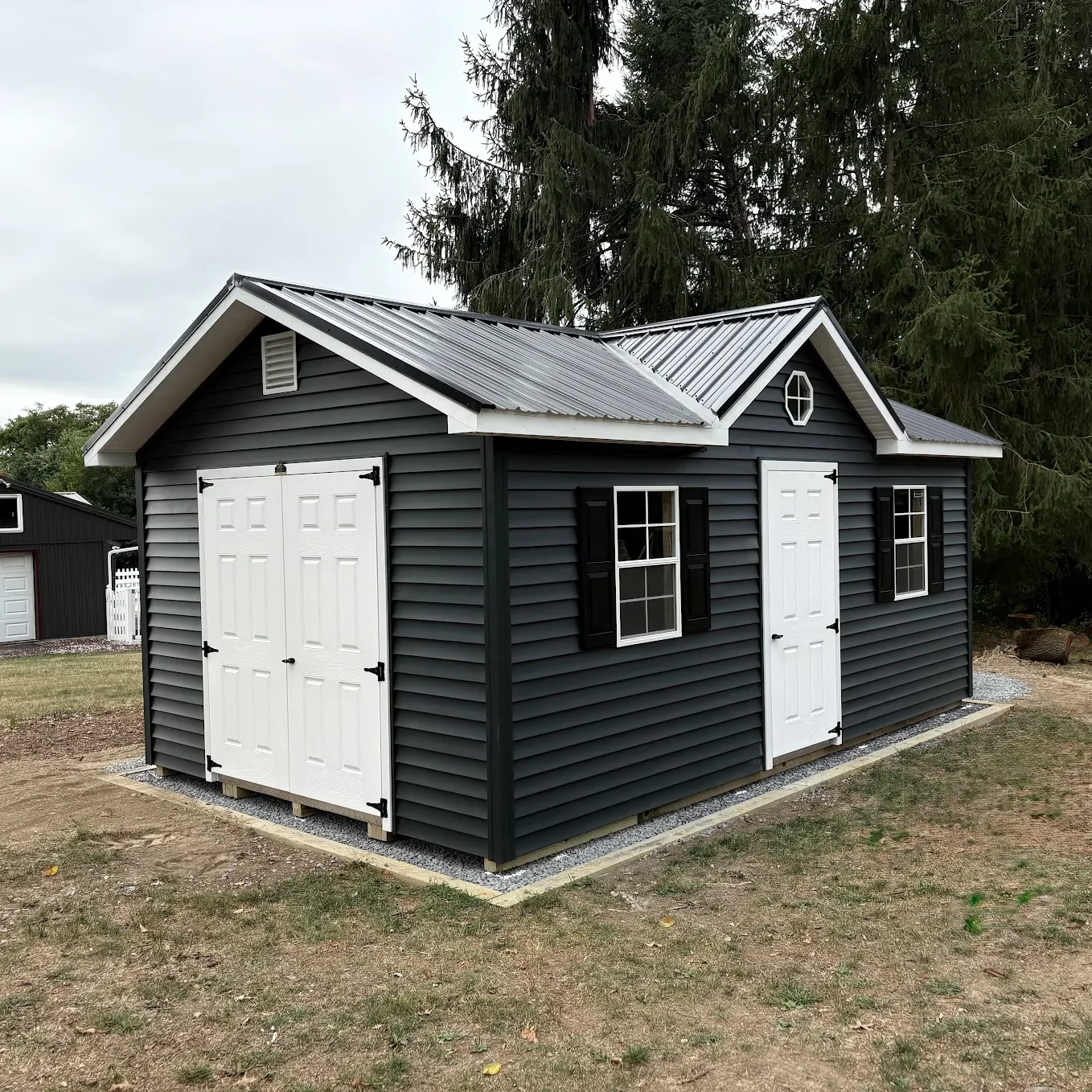 Custom backyard shed, dark exterior with white double doors and accents.